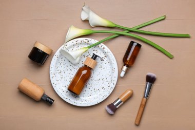 Kozmetik ürünleri, makyaj fırçaları ve ahşap arkaplanda zambaklarla kompozisyon