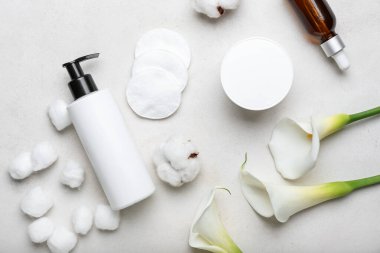 Composition with cosmetic products, cotton pads, balls and flowers on light background
