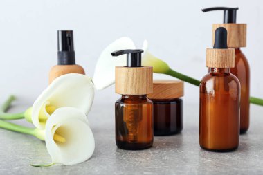 Işıklı arka planda farklı kozmetik ürünleri ve zambaklar, yakın plan