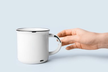 Hafif arka planda fincanı olan kadın el, yakın plan.