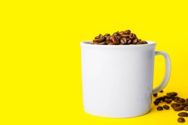 Sarı zemin üzerinde kahve çekirdekleri olan seramik bardak.