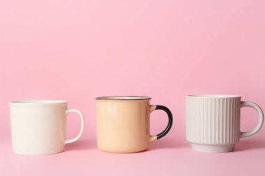 Pembe arka planda farklı fincanlar