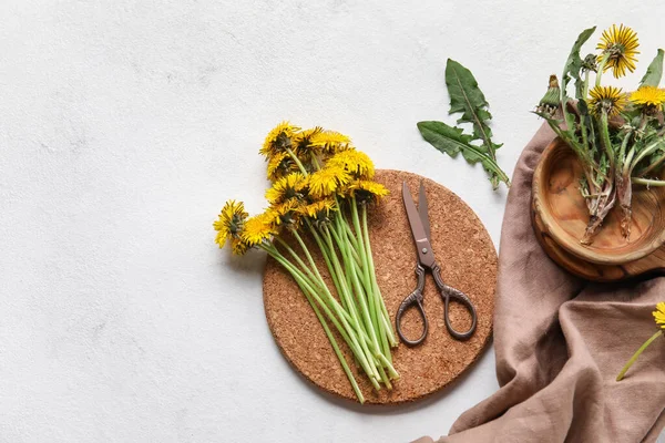 Beyaz arka planda karahindibalar, makas, kase ve peçete.