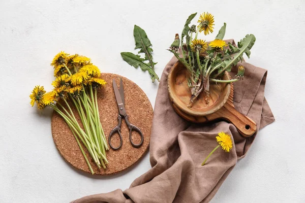 Beyaz arka planda karahindibalar, makas, kase ve peçete.
