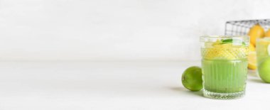 Bardakta buzlu narenciye yeşil çayı açık arkaplanda ve metin için yer var.