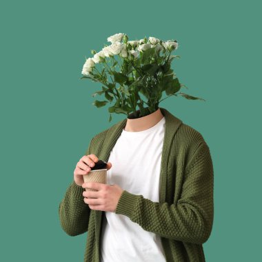 Kafası yerine güzel güller ve yeşil arka planda bir fincan kahve olan bir adam.