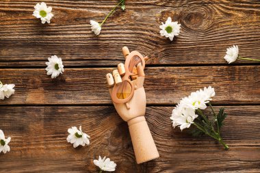 Güneş gözlüklü dekoratif eller ve ahşap arka planda kasımpatı çiçekleri.