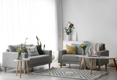 Stylish interior of living room with comfortable sofas and floral decor