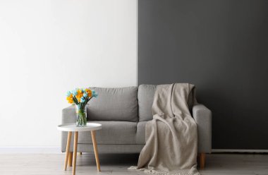 Oturma odasının şık bir iç mekanı. Masasında güzel laleler olan bir vazo ve kanepe.