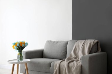 Masasında güzel laleler ve oturma odasında rahat bir kanepe olan bir vazo.