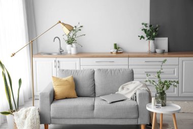 Çiçek açan ağaç dalları olan vazo ve aydınlık odanın içinde modern dizüstü bilgisayarlı kanepe.