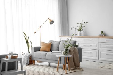 Rahat kanepesi ve vazoda çiçek açan ağaç dalları olan ışık odasının içinde.