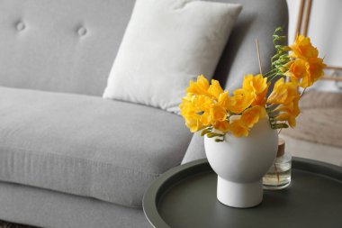 Kanepenin yanındaki vazoda güzel çiçekler ve sazlıklar var.