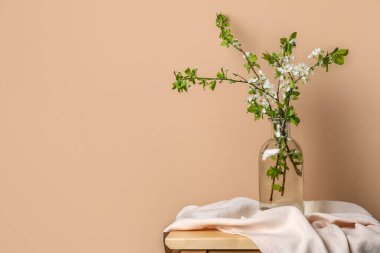 Renk duvarının yanındaki masada çiçek açan ağaç dalları olan vazo.