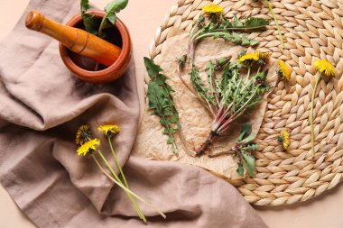 Karahindiba, havan, tokmak ve bej arkaplanlı peçeteli hasır.