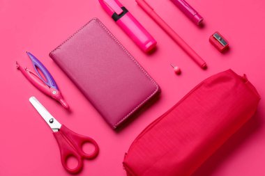 Pembe arka planda kırtasiye malzemeleri olan kırmızı kalem kutusu.