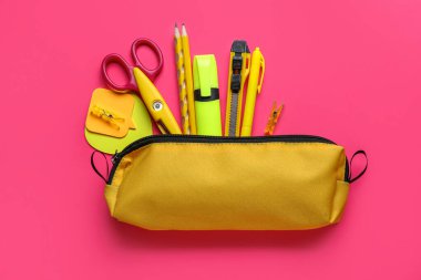 Pembe arka planda kırtasiye malzemesi olan sarı kalem çantası.