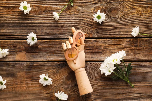 Güneş gözlüklü dekoratif eller ve ahşap arka planda kasımpatı çiçekleri.