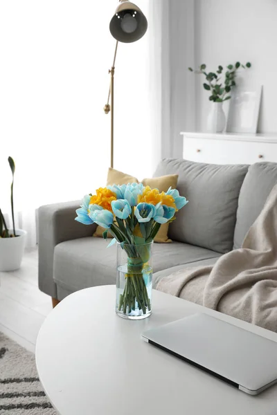 リビングルームでテーブルの上にウクライナのフラグとラップトップの色の美しいチューリップの花束で花瓶 — ストック写真