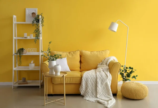 Rahat kanepesi, raf ünitesi ve çiçek dekoru olan oturma odasının içinde.