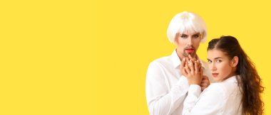 Portrait of young transgender couple on yellow background with space for text