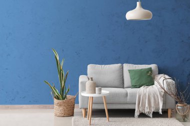 Şık bir kanepe ve mavi duvarın yanındaki masa.