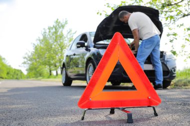 Red emergency stop sign and man near broken car