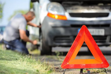 Red emergency stop sign, man and broken car on background, closeup