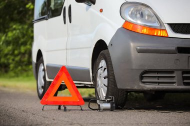 Acil durum üçgeni dur işareti ve yolda bozuk bir araba.