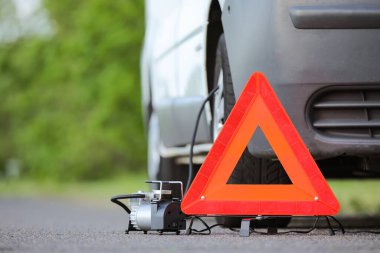Acil durum üçgeni dur işareti ve yolda bozuk bir araba.
