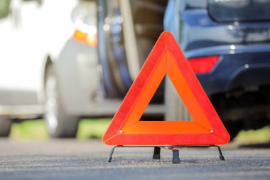 Emergency triangle stop sign and broken cars on background