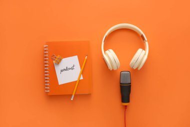 Mikrofon, kulaklık, kelime PODCAST ile kağıt ve renk arkaplanı üzerine not defteri
