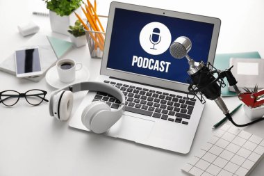 Ekranda PODCAST sözcüğü, mikrofon ve kulaklıklı modern dizüstü bilgisayar