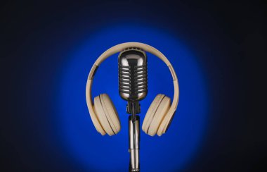 Koyu arkaplanlı kulaklıklı modern mikrofon, yakın plan.