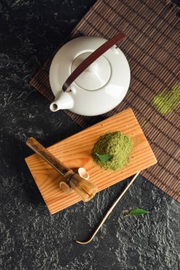 Tahta ahşap tahta, toz kibrit çayı ve koyu arkaplanda çaydanlık.