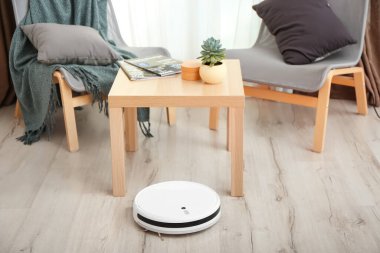Modern robot süpürgesi odasındaki ahşap masanın yanında.
