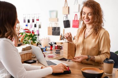 Mağazada müşteriye hizmet eden kadın işyeri sahibi