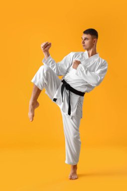 Adam sarı arka planda karate yapıyor.