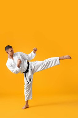 Adam sarı arka planda karate yapıyor.