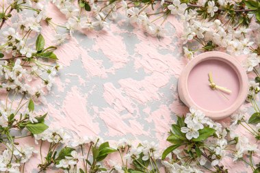 Pembe arka planda çiçek açan bahar dalları ve alarmlı saatten oluşan çerçeve