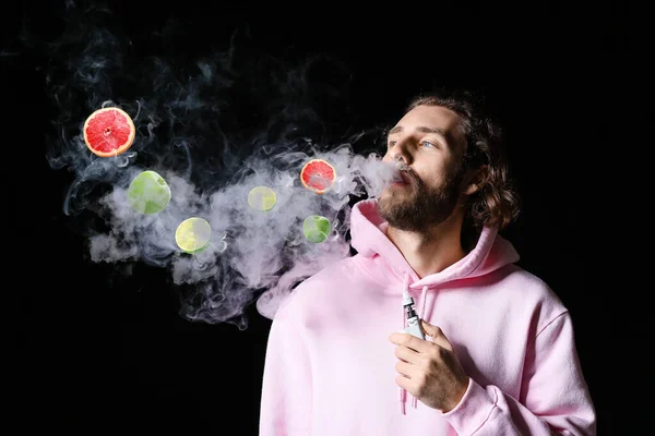 Young Man Smoking Electronic Cigarette Fruit Flavor Black Background — Stockfoto