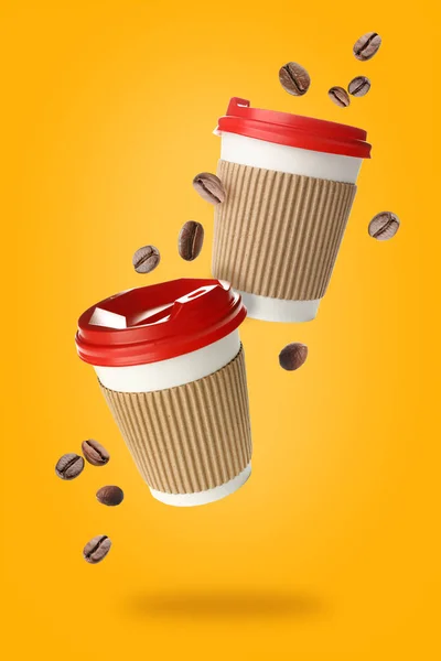 Flying takeaway coffee cups and beans on yellow background