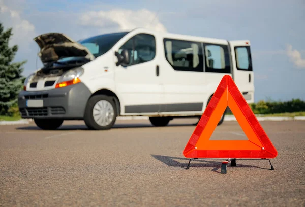 Emergency triangle stop sign and broken car on road