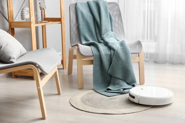 客厅椅子旁边地毯上的现代机器人吸尘器 — 图库照片
