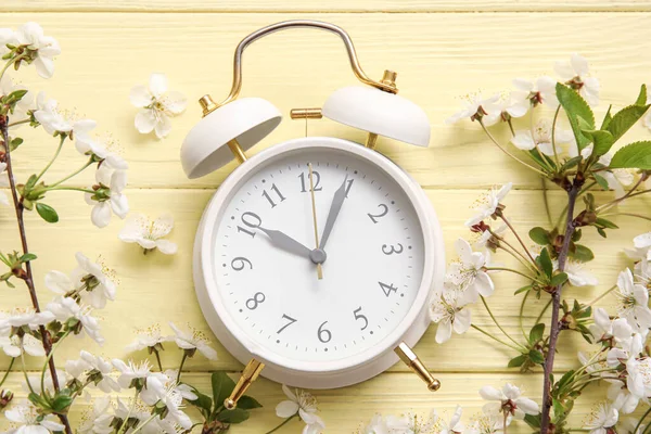Blooming Spring Branches Alarm Clock Yellow Wooden Background — Stock fotografie