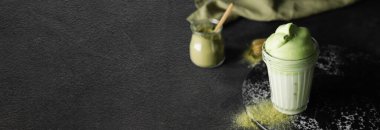 Glass of tasty dalgona matcha latte on dark background with space for text