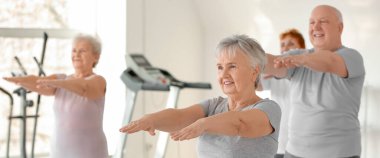 Spor salonunda egzersiz yapan bir grup yaşlı insan.