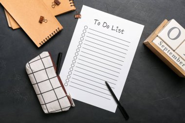 Liste, defter, takvim ve kalem kutusu boş. Koyu arkaplanda kırtasiye malzemeleri var.