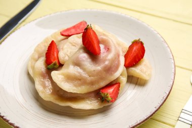 Ahşap arka planda lezzetli çilekli hamur tatlısı tabağı, yakın plan.