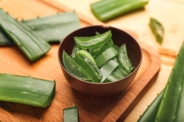 Ahşap tahta, kâse ve taze kesilmiş aloe yapraklı masa, yakın plan.